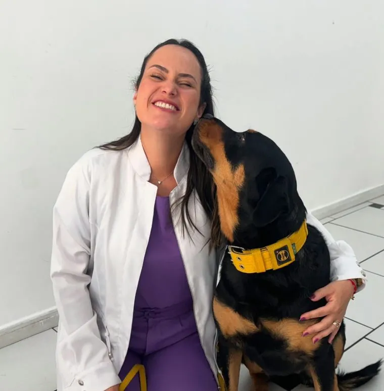 M.V Roberta rindo enquanto um cão lambe seu rosto
